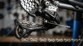 Механизм переключения скоростей велосипеда - цепь, кассета и задний переключатель с роликами в момент смены передачи Механизм переключения скоростей велосипеда - цепь, кассета и задний переключатель с роликами в момент смены передачи